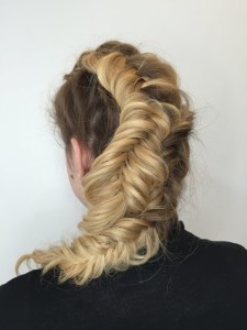 A woman with blonde hair styled in a fishtail braid showcases one of the classic hair styles against a white background.