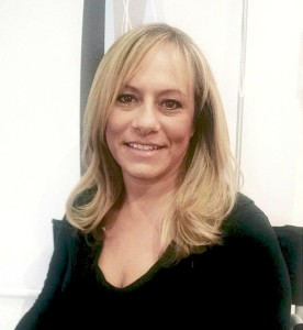 A woman with long blonde hair, freshly styled from Salon Today 200, wearing a black top smiles while looking at the camera.