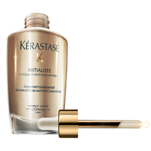 A bottle of Kérastase Initialiste Advanced Scalp and Hair Concentrate with a gold dropper cap, laying next to the bottle.