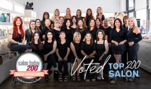 Group photo of salon staff in a bright, modern salon with shelves of products behind them. The image features a badge reading "Salon Today 200, 2024 Honoree" and the text "Voted Top 200 Salon.